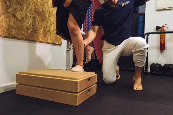 Fisioterapeuta de Invicto guiando un ejercicio de subida al cajón para la rodilla