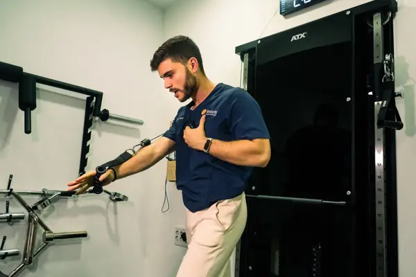 Fisioterapeuta de Invicto realizando un ejercicio de hombro con polea en la sala de rehabilitación